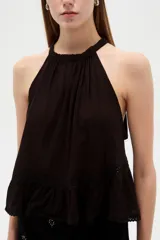 Top blanco de algodón con cuello halter, diseño holgado y detalle de encaje en el borde inferior.