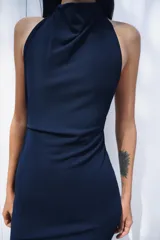Vestido largo de corte fluido con cuello halter y espalda descubierta. Presenta un detalle de drapeado lateral y bajo recto.