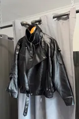 Campera estilo biker de cuero sintético negro, con cierre frontal, cuello solapa y cinturón ajustable en la cintura.