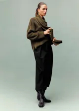 Pantalón de vestir negro de corte recto y largo, con detalle de pliegues frontales, dos bolsillos laterales y cierre de cremallera.