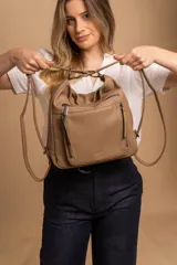 Cartera mochila versátil de cuero sintético con textura granulada, color negro. Cuenta con múltiples bolsillos frontales con cierre, correas ajustables que permiten su uso tanto como cartera de hombro o como mochila, y herrajes metálicos.