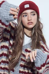 Cardigan de tejido de punto con diseño de rayas horizontales en tonos azul, gris y crema. Presenta escote en V, cierre frontal con botones grandes y mangas largas con puños anchos acanalados.