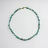 Collar de cuentas irregulares de piedra natural amazonita en tonos turquesa y verde agua, con cierre y detalles metálicos con baño de oro.