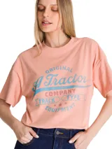 Remera de corte boxy y relajado, color rosado, con cuello redondo y mangas cortas. Presenta un estampado gráfico frontal de estilo retro con tipografía en tonos azules y rojos.