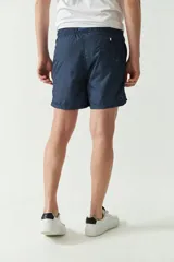 Short de baño estampado con diseño geométrico en tonos verdes, cintura elástica con cordón ajustable, bolsillos laterales y bolsillo trasero.