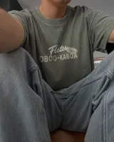 Remera oversize de color verde militar con efecto acid wash y diseño estampado en la espalda que incluye un camión de remolque y texto alusivo.