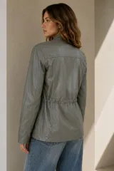 Campera estilo cazadora color verde militar de cuero ovino italiano, con cuello mao, cierre frontal, bolsillos frontales con solapa y cordón interno ajustable en la cintura.