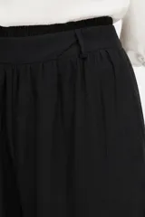 Pantalón de viscosa color negro, holgado de tiro alto, con bolsillos laterales, detalles de frunces en la cintura y botamangas elastizadas.