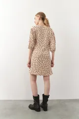 Vestido corto con estampado animal print en tonos beige y negro. Tiene mangas tres cuartos con elástico, cut-out en el frente y lazo.