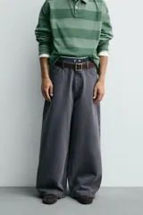 Pantalón wide fit color gris oscuro, confeccionado en tejido ligero de algodón. Cuenta con cinco bolsillos y efecto lavado. Cierre frontal con cremallera y botón.