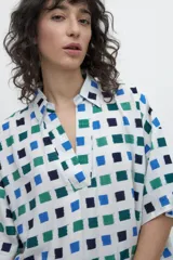 Blusa oversized con estampa geométrica de cuadrados azules y verdes sobre fondo blanco.