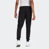 Pantalón deportivo Adidas modelo Essentials, color negro con las tres tiras características de la marca en blanco a los costados. Presenta cintura elástica con cordón de ajuste, puños acanalados en los tobillos y logo de la marca bordado en el frente.