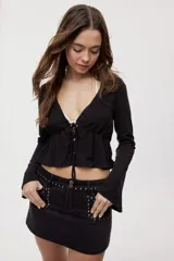 Blusa manga larga de color negro con escote en V profundo y lazo ajustable en el frente, confeccionada en tejido liviano con corte evasé.