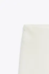 Falda midi de satén color blanco, de corte asimétrico y con encaje en el ruedo.