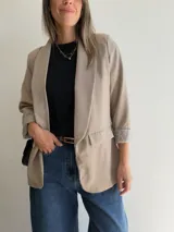 Blazer sastrero de corte clásico con solapas frontales y bolsillos con solapa. Presenta mangas largas con puños vueltos y un diseño forrado que ofrece una caída estructurada y elegante.