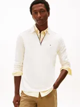 Chomba de manga larga Tommy Hilfiger color blanco, de corte regular y tejido de algodón suave. Presenta cuello clásico, cierre frontal parcial con cremallera y ribetes tricolores, además del logo bordado en el pecho.