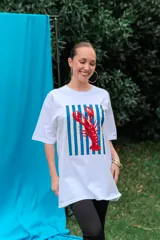 Remerón de algodón blanco con corte oversize y cuello redondo, que presenta un estampado frontal con diseño de una lata de sardinas sobre fondo de rayas.