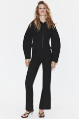 Chaqueta entallada de tejido efecto neopreno en color negro, con cuello solapa amplio, cierre frontal con cremallera y mangas largas abullonadas.