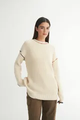 Buzo color crema tejido en punto, con cuello redondo y calce oversize. Presenta detalles de cambio de color en cuello, hombros y puños.