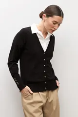 Cardigan negro con escote en V, manga larga y cierre frontal con botones pequeños. Presenta puños acanalados con detalle de botones decorativos.
