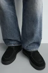Bota de caña media con cordones, confeccionada en piel con acabado en serraje. Presenta horma redonda, forro interior de pelo sintético y suela de goma con volumen.