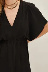 Vestido midi de color negro con escote en V, mangas cortas y cintura elástica. Presenta un diseño fluido con una abertura frontal central en la falda.