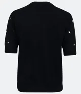 Blusa de punto negra con escote redondo, manga corta y apliques de corazones dorados.