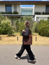 Bolso tipo tote bag de cuero trenzado a mano, en tonos marrón y negro, con asas trenzadas.