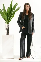 Blazer de mujer color gris oscuro con textura de jean/lino, corte oversize, hombreras, bolsillos frontales y pespuntes a contratono. Cierre frontal con botones.