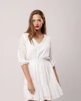 Vestido corto negro de broderie de algodón, con escote en V, mangas tres cuartos, cintura elastizada, falda corte A con volado y forro interior.