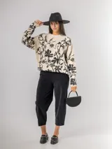 Sweater de punto con calce oversized, fondo color crudo y diseño estampado de flores en color negro. Presenta cuello redondo y mangas largas.