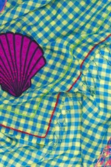 Chal o pañuelo cuadrado con estampado a cuadros vichy en tonos azul y amarillo claro. Presenta apliques bordados de temática marina (pez, caballito de mar, pulpo, estrellas de mar y corales) y bordes con flecos.