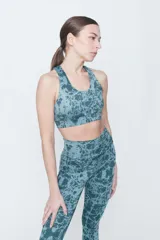 Top deportivo de lycra color verde con estampado abstracto en tonos verde oscuro y celeste. Espalda cruzada y compresión alta.