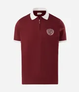 Remera polo azul marino con cuello y puños en contraste de color blanco, manga corta y cierre frontal parcial. Presenta un escudo bordado en el pecho.