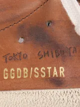 Zapatillas Golden Goose modelo Super-Star de cuero color marrón con efecto desgastado. Presentan cordones color crema, suela de goma envejecida y detalles de escritura grabada en el lateral y la puntera.