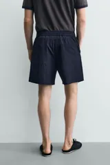 Bermuda relaxed fit de color azul marino confeccionada en tejido fluido con mezcla de viscosa, cintura elástica con cordón interior y bolsillos frontales.
