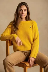 Sweater de punto en color amarillo, con diseño oversize, cuello redondo y manga larga. Presenta un pequeño bordado de un velero en la parte superior del pecho.