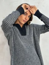Sweater de punto acanalado color gris, con cuello polo y escote en V. Diseño holgado con mangas largas y aberturas laterales en el dobladillo.