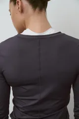 Remera deportiva gris de manga larga, con cuello redondo y corte ajustado, confeccionada en tejido funcional con tecnología DryMove.