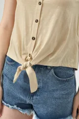 Musculosa color beige con escote en V, sin mangas, con botones y nudo en la parte inferior.