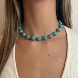 Collar corto de cuentas redondas color turquesa y cuentas cilíndricas color fucsia.
