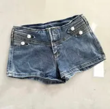 Short de denim azul tiro bajo, con diseño de doble botonadura metálica en la parte frontal y calce ajustado.