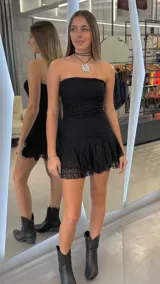 Vestido corto strapless de encaje negro, con diseño ajustado al cuerpo y falda con volado en el ruedo.