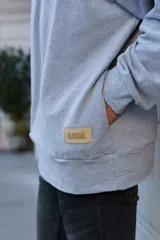 Buzo gris de algodón con cierre parcial en el cuello y bolsillo escondido.