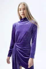 Vestido corto de terciopelo violeta con cuello alto, mangas largas y drapeado en la falda.