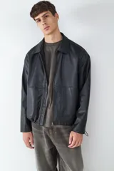 Campera de efecto cuero con cuello camisero, cierre frontal con cremallera y bolsillos laterales amplios. Presenta un diseño de corte recto y acabado liso.