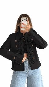 Campera estilo militar negro con botonadura dorada y detalles de cordones decorativos en el frente.