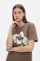 Remera de algodón color beige con estampado frontal de un corazón rosado que contiene un moño. Tiene cuello redondo y mangas cortas.