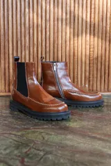 Bota de cuero color marrón, de caña media, con elástico lateral y suela track.