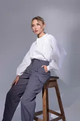 Pantalón gris de tiro alto con pinzas, bolsillos cargo laterales y ruedo ajustable con botones.